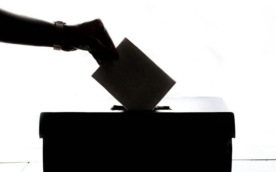 A hand placing a ballot into a ballot box