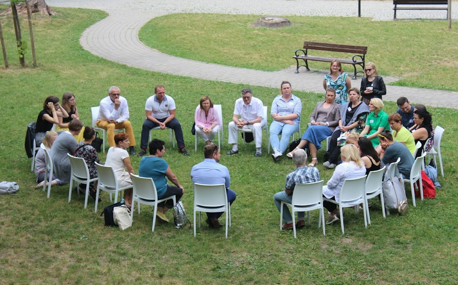 Neighbors seated in a circle at an outdoor community meeting