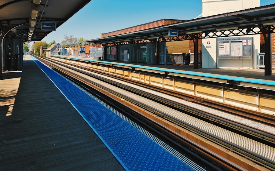 A sunlit commuter rail platform and tracks